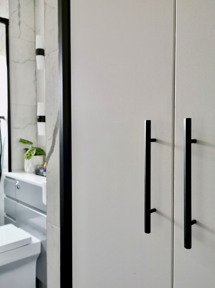 Стильный дизайн: маленькая ванная комната в современном стиле с плоскими фасадами, серыми фасадами, душем без бортиков, унитазом-моноблоком, белой плиткой, керамической плиткой, белыми стенами, полом из керамогранита, душевой кабиной, монолитной раковиной, черным полом, душем с раздвижными дверями, белой столешницей, тумбой под одну раковину и встроенной тумбой для на участке и в саду - последний тренд
