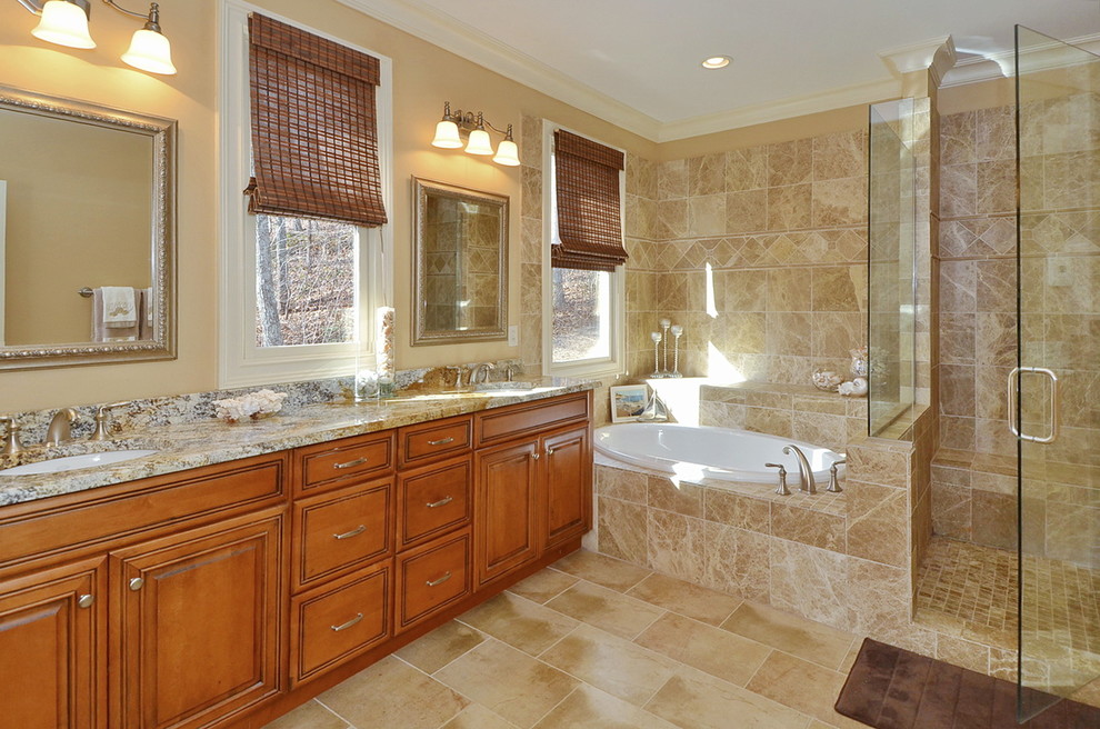 Foto di una stanza da bagno tradizionale con lavabo sottopiano, ante in legno scuro, vasca da incasso e piastrelle beige