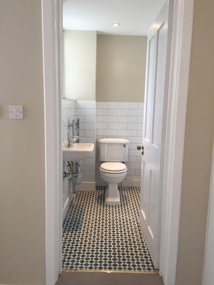 Photo of a small victorian ensuite bathroom in London with a wall-mounted sink, an alcove bath, a shower/bath combination, a two-piece toilet, white tiles, metro tiles, green walls and ceramic flooring.
