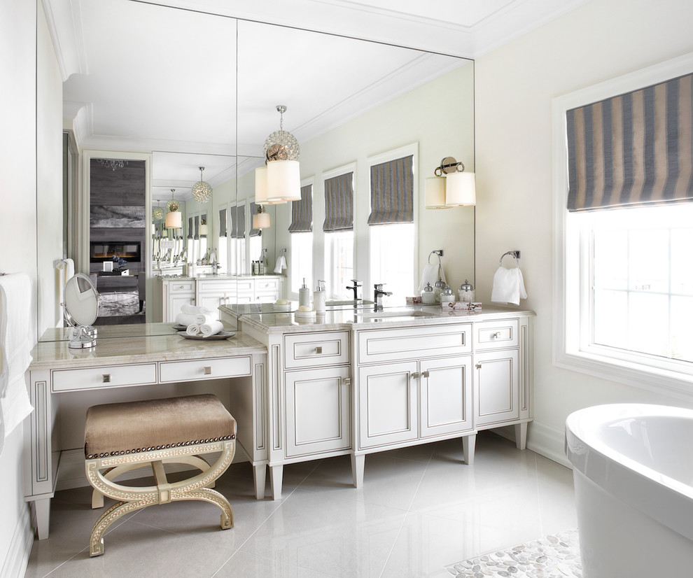 Идея дизайна: ванная комната в классическом стиле с белыми фасадами, отдельно стоящей ванной, бежевыми стенами, врезной раковиной, белым полом и фасадами с утопленной филенкой