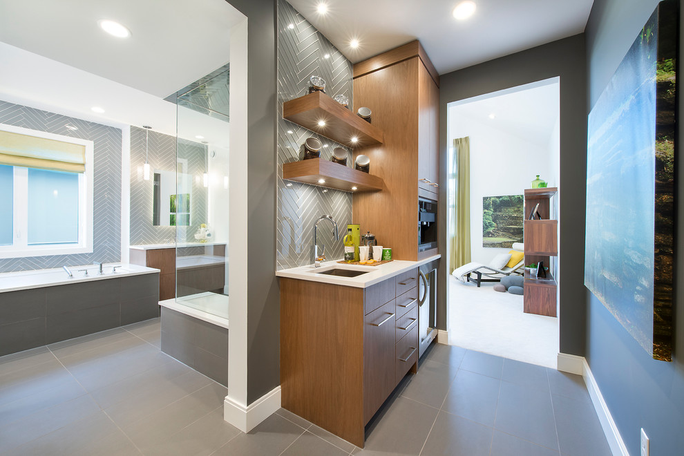 Foto på ett funkis badrum, med ett undermonterad handfat, släta luckor, skåp i mellenmörkt trä, ett undermonterat badkar, en hörndusch, grå kakel, glaskakel och grå väggar