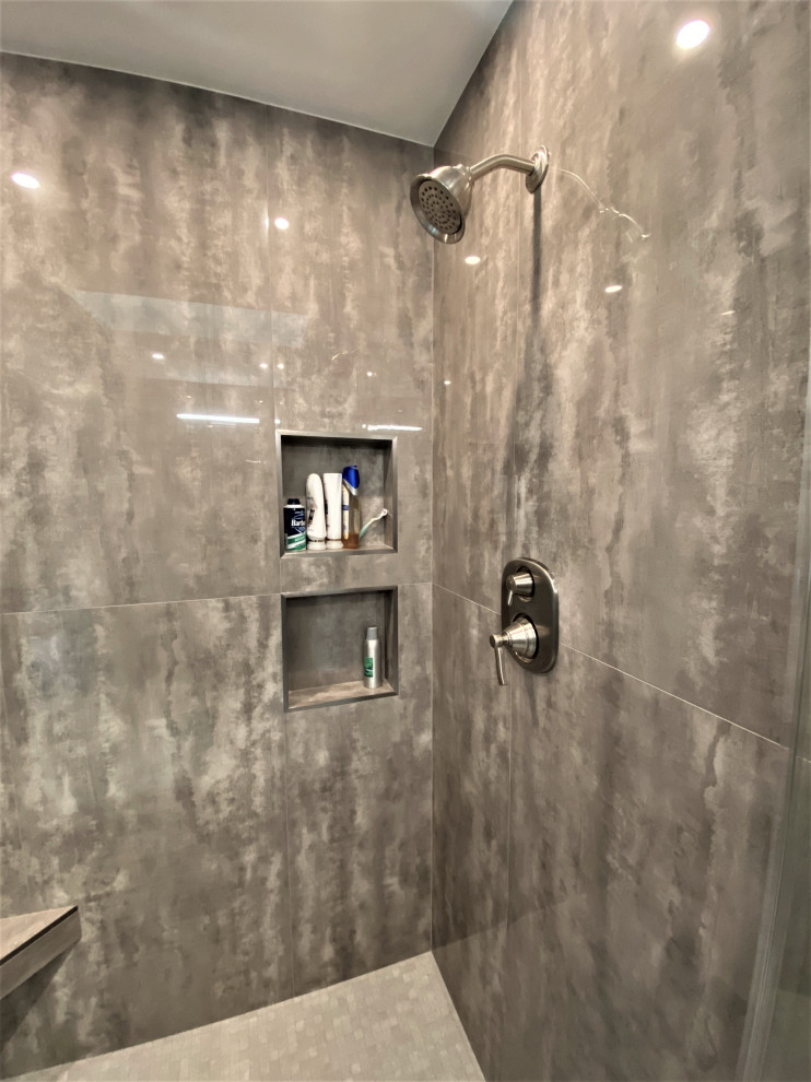 Photo of a medium sized contemporary ensuite bathroom in DC Metro with flat-panel cabinets, grey cabinets, an alcove shower, a two-piece toilet, grey tiles, porcelain tiles, grey walls, porcelain flooring, a submerged sink, engineered stone worktops, grey floors, a hinged door, grey worktops, a shower bench, double sinks and a floating vanity unit.