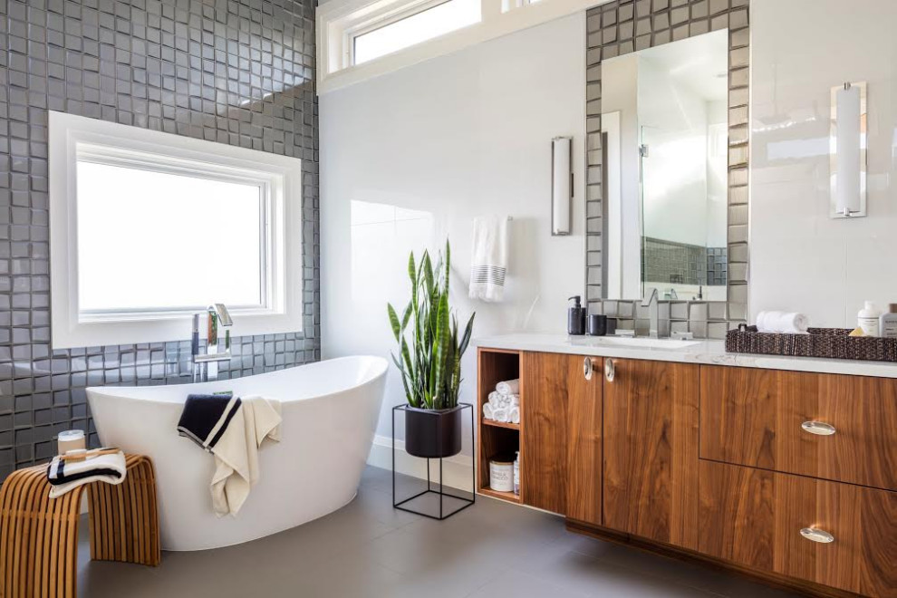 Cette photo montre une salle de bain tendance en bois brun avec un placard à porte plane, une baignoire indépendante, un carrelage gris, un mur blanc, un lavabo encastré, un sol gris, un plan de toilette blanc, meuble double vasque et meuble-lavabo encastré.