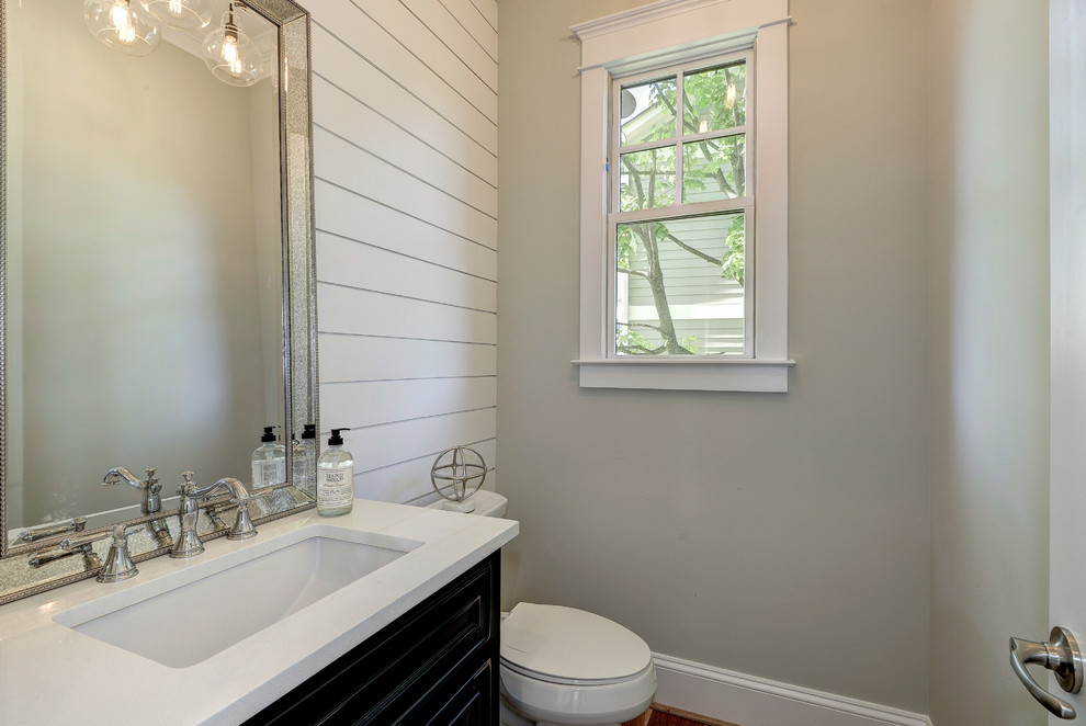Ejemplo de cuarto de baño moderno pequeño con puertas de armario de madera en tonos medios, sanitario de una pieza, paredes grises, suelo de madera clara, aseo y ducha, lavabo encastrado y encimera de granito
