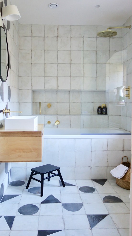 Bild på ett mellanstort nordiskt beige beige badrum för barn, med skåp i ljust trä, ett platsbyggt badkar, en dusch/badkar-kombination, svart och vit kakel, porslinskakel, vita väggar, klinkergolv i porslin, träbänkskiva, flerfärgat golv, ett fristående handfat och med dusch som är öppen