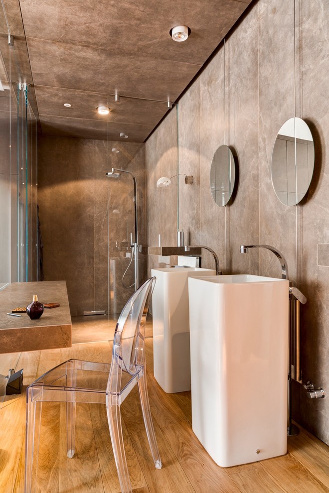 Ispirazione per una stanza da bagno padronale minimalista con lavabo a colonna, doccia aperta, WC sospeso, piastrelle marroni, piastrelle in ceramica, pareti marroni e parquet chiaro