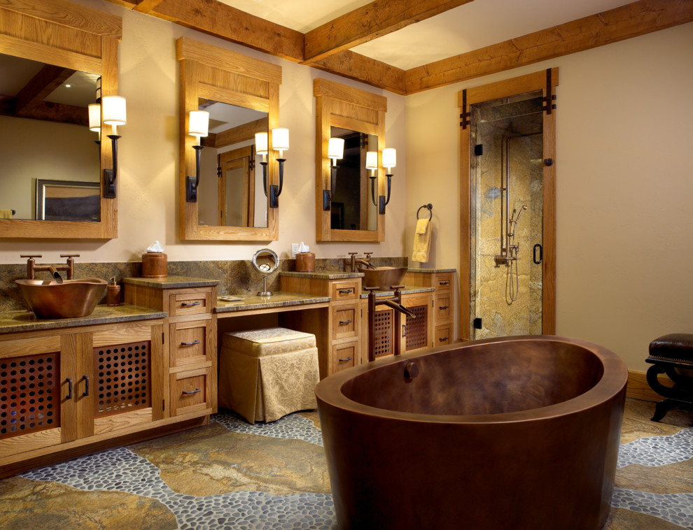 Пример оригинального дизайна: ванная комната в стиле рустика с настольной раковиной, фасадами с утопленной филенкой, фасадами цвета дерева среднего тона, отдельно стоящей ванной, душем в нише и полом из галечной плитки