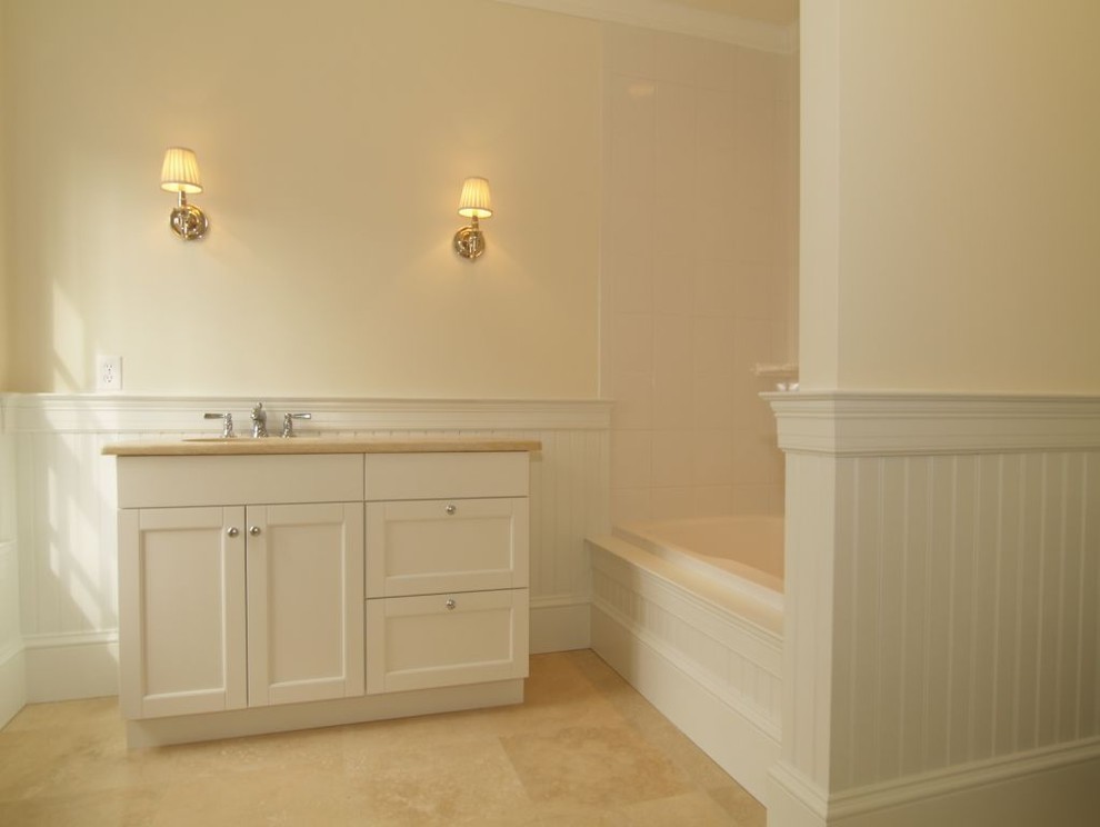 Foto di una stanza da bagno con doccia di medie dimensioni con ante in stile shaker, ante bianche, vasca ad angolo, vasca/doccia, piastrelle in ceramica, pareti gialle, pavimento in travertino, lavabo sottopiano e top in granito