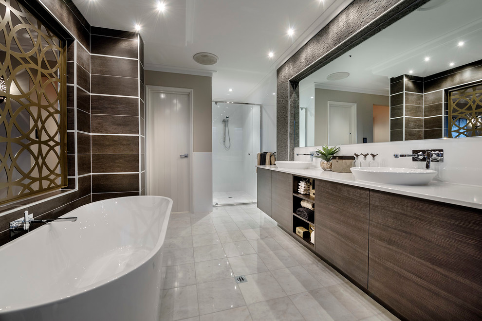 На фото: большая главная ванная комната в стиле модернизм с настольной раковиной, плоскими фасадами, темными деревянными фасадами, отдельно стоящей ванной, коричневой плиткой и коричневыми стенами с