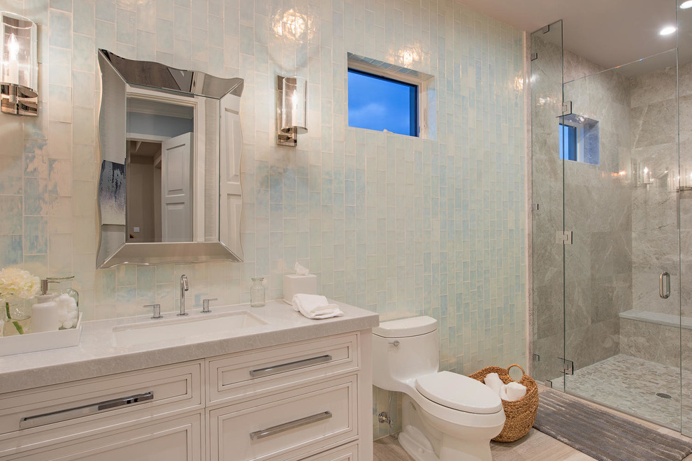 Klassisk inredning av ett mycket stort badrum med dusch, med ett undermonterad handfat, vita skåp, marmorbänkskiva, en dusch i en alkov och blå kakel