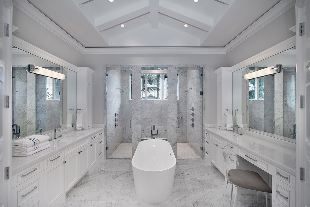 Пример оригинального дизайна: главная ванная комната в стиле неоклассика (современная классика) с отдельно стоящей ванной, двойным душем, фасадами с утопленной филенкой, белыми фасадами, серыми стенами, врезной раковиной, серым полом, серой столешницей и зеркалом с подсветкой