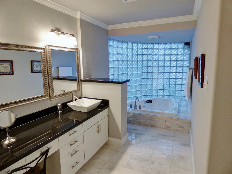 Foto på ett mycket stort funkis en-suite badrum, med släta luckor, vita skåp, ett platsbyggt badkar, en toalettstol med separat cisternkåpa, grå kakel, marmorkakel, grå väggar, marmorgolv, ett fristående handfat och granitbänkskiva