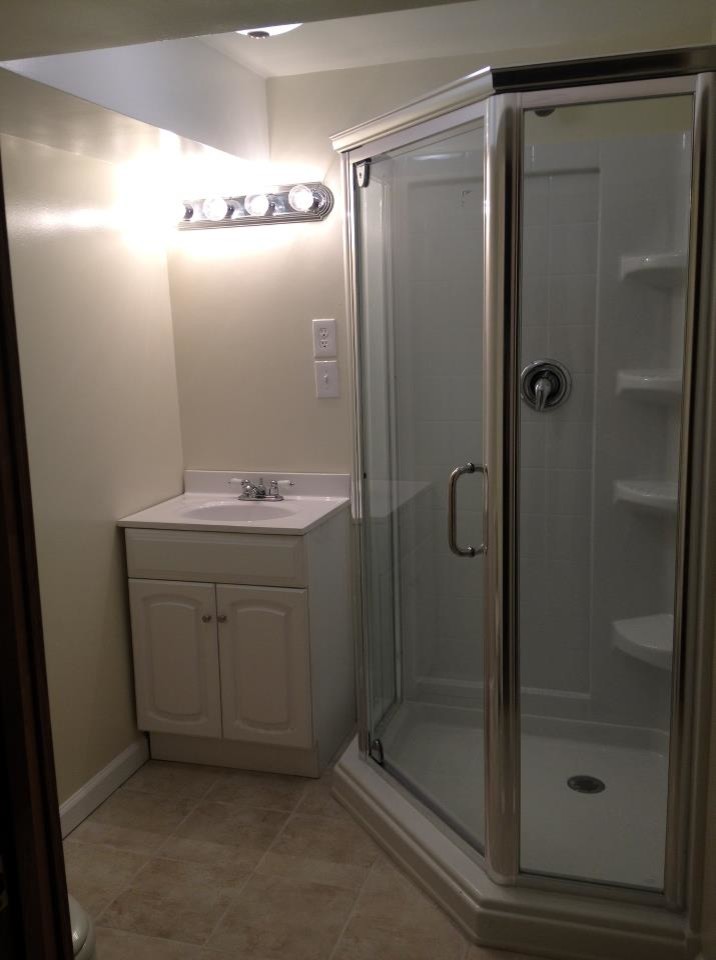 Cette image montre une petite salle d'eau traditionnelle avec un placard avec porte à panneau surélevé, des portes de placard blanches, une douche d'angle, un carrelage blanc, du carrelage en travertin, un mur beige, un sol en travertin, une grande vasque, un plan de toilette en stratifié, un sol beige et une cabine de douche à porte battante.