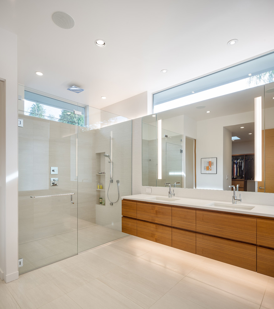 На фото: главная ванная комната в стиле модернизм с плоскими фасадами, фасадами цвета дерева среднего тона, душем в нише, врезной раковиной, бежевым полом, душем с распашными дверями, белой столешницей и зеркалом с подсветкой с