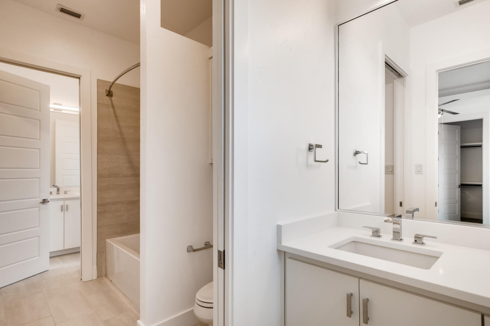 Exempel på ett stort modernt vit vitt badrum med dusch, med släta luckor, vita skåp, ett platsbyggt badkar, en öppen dusch, en toalettstol med hel cisternkåpa, grå kakel, marmorkakel, vita väggar, klinkergolv i keramik, ett integrerad handfat, marmorbänkskiva, beiget golv och dusch med duschdraperi