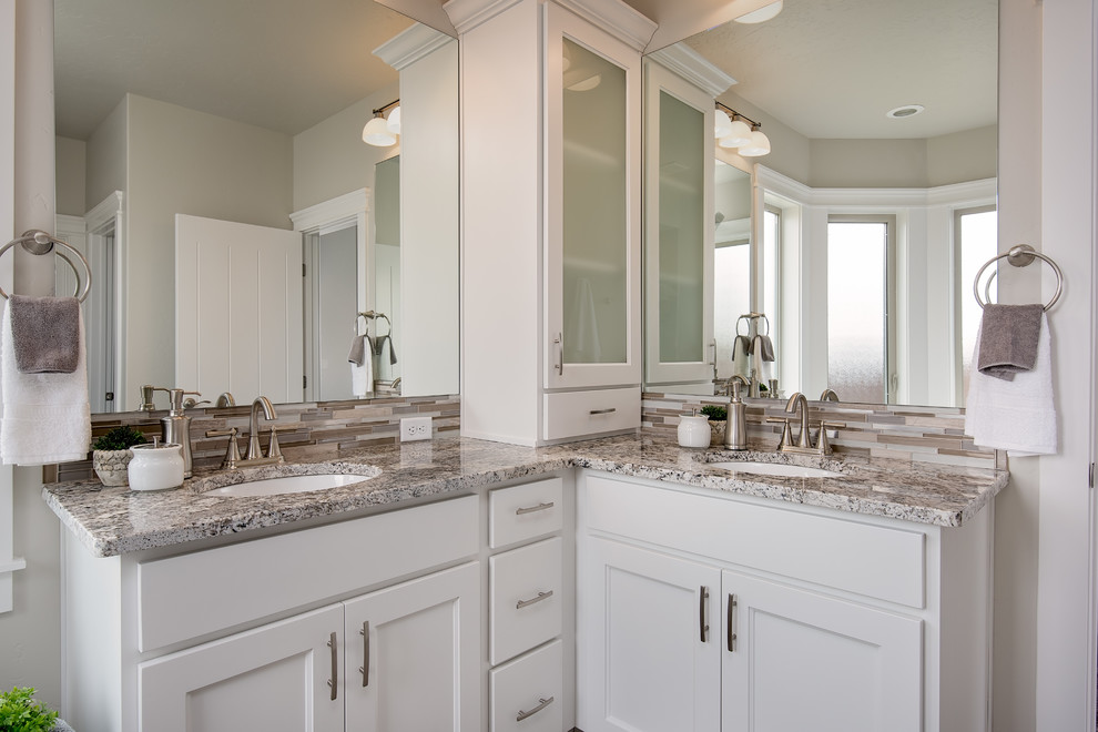 Inspiration for a large traditional ensuite bathroom in Boise with raised-panel cabinets, white cabinets, a freestanding bath, a corner shower, a two-piece toilet, grey tiles, porcelain tiles, porcelain flooring, a submerged sink, granite worktops and grey walls.