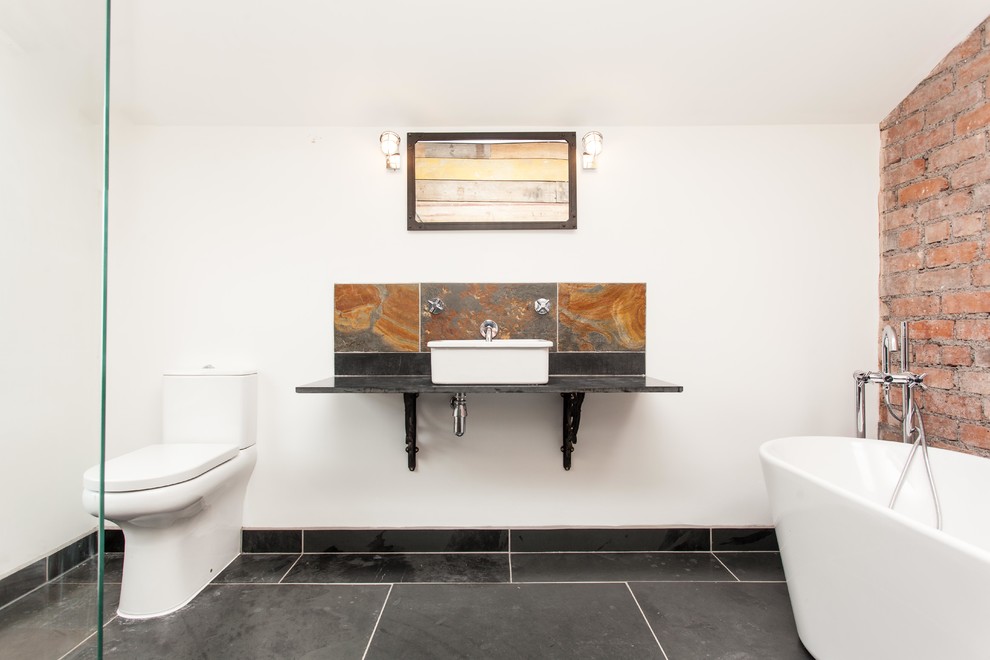Foto di una stanza da bagno con doccia contemporanea di medie dimensioni con vasca freestanding, doccia aperta, WC monopezzo, piastrelle nere, piastrelle in pietra, pareti bianche e pavimento in ardesia