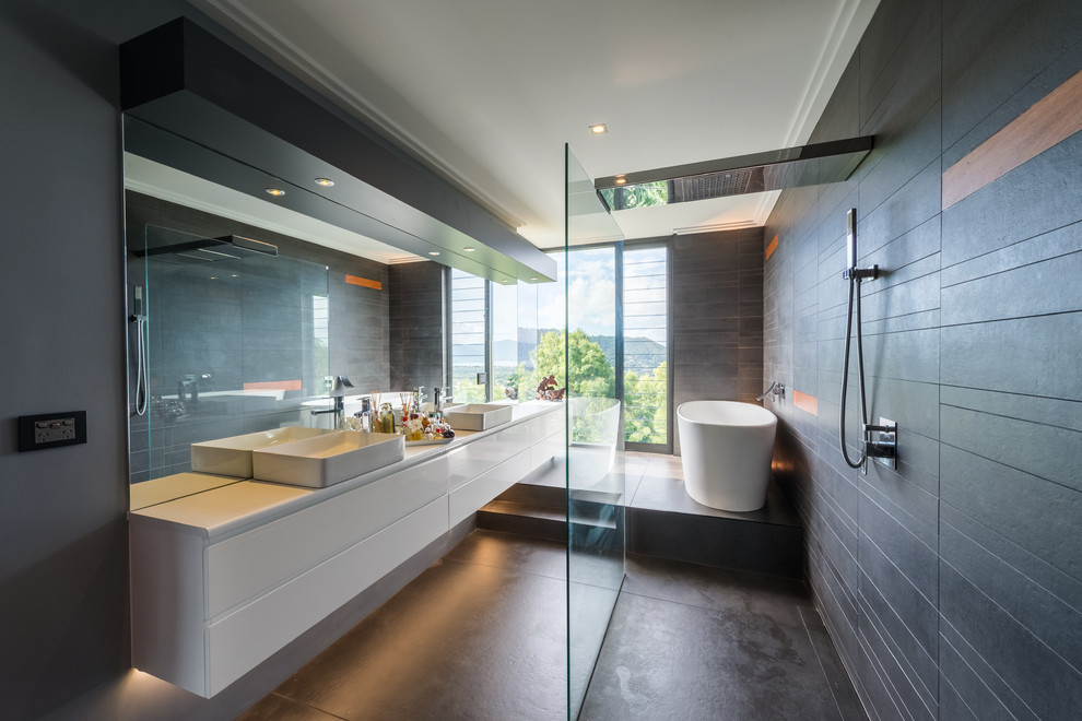 На фото: главная ванная комната в стиле модернизм с плоскими фасадами, белыми фасадами, отдельно стоящей ванной, открытым душем, черной плиткой, черными стенами, настольной раковиной и черным полом