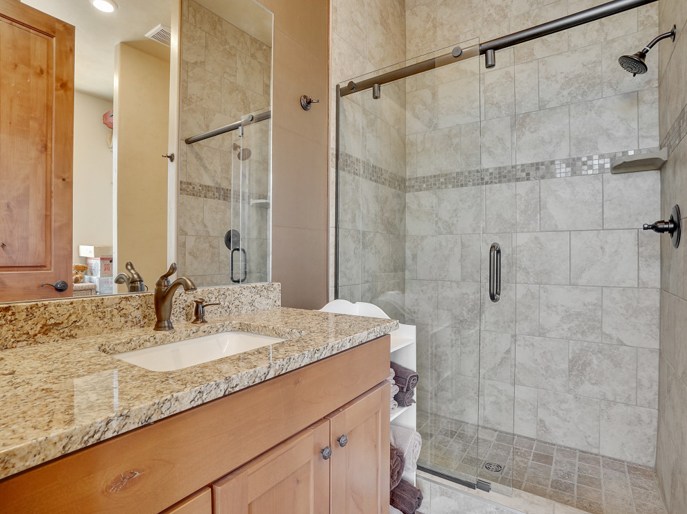 Exempel på ett mellanstort modernt beige beige en-suite badrum, med luckor med infälld panel, skåp i ljust trä, en dusch i en alkov, en toalettstol med separat cisternkåpa, grå kakel, keramikplattor, beige väggar, vinylgolv, ett undermonterad handfat, laminatbänkskiva och dusch med skjutdörr