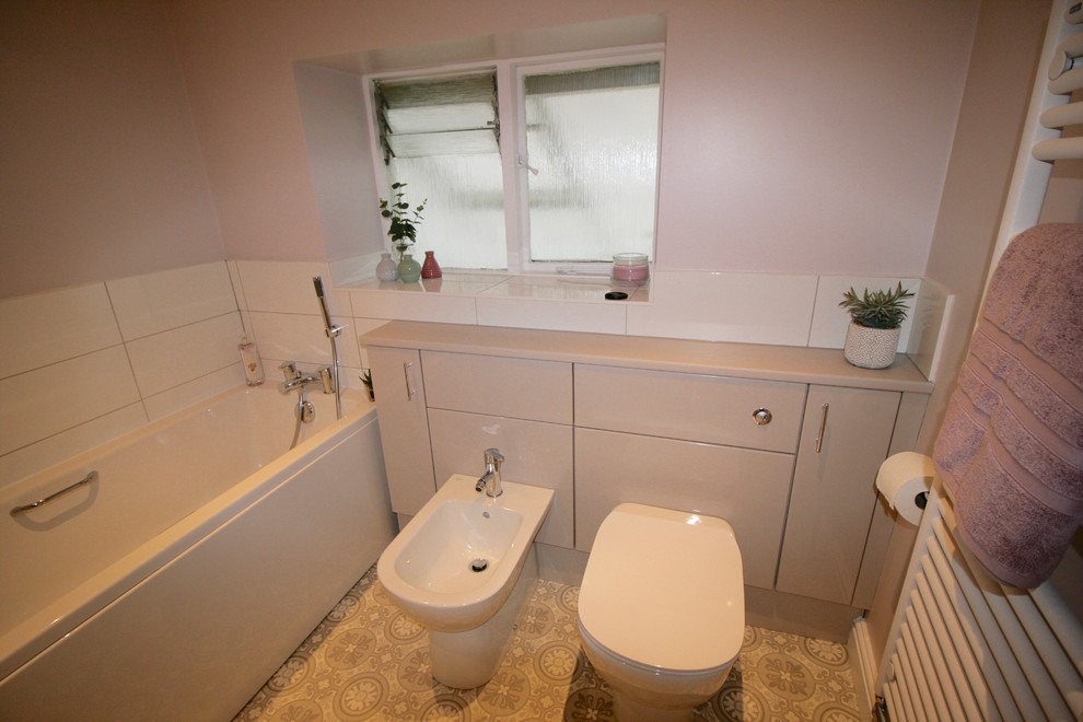 Стильный дизайн: маленькая детская ванная комната в современном стиле с плоскими фасадами, серыми фасадами, накладной ванной, унитазом-моноблоком, белой плиткой, керамической плиткой, розовыми стенами, полом из винила, консольной раковиной и столешницей из ламината для на участке и в саду - последний тренд
