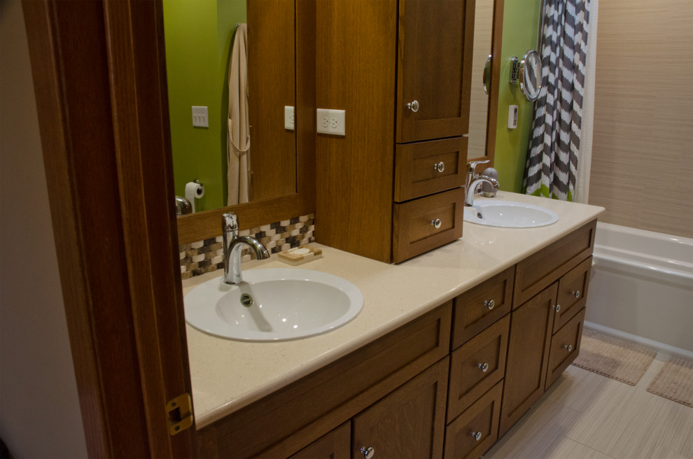 This is an example of a medium sized contemporary ensuite bathroom in Minneapolis with a built-in sink, recessed-panel cabinets, dark wood cabinets, laminate worktops, a built-in bath, a shower/bath combination, a two-piece toilet, beige tiles, ceramic tiles, green walls and porcelain flooring.