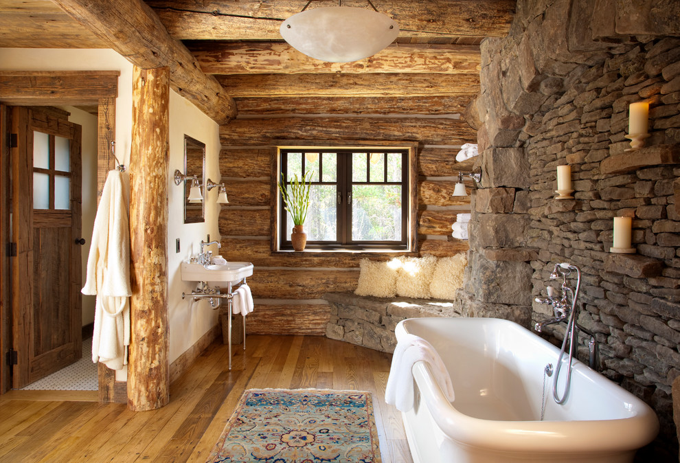 Uriges Badezimmer mit Waschtischkonsole, freistehender Badewanne und Steinwänden in Sonstige
