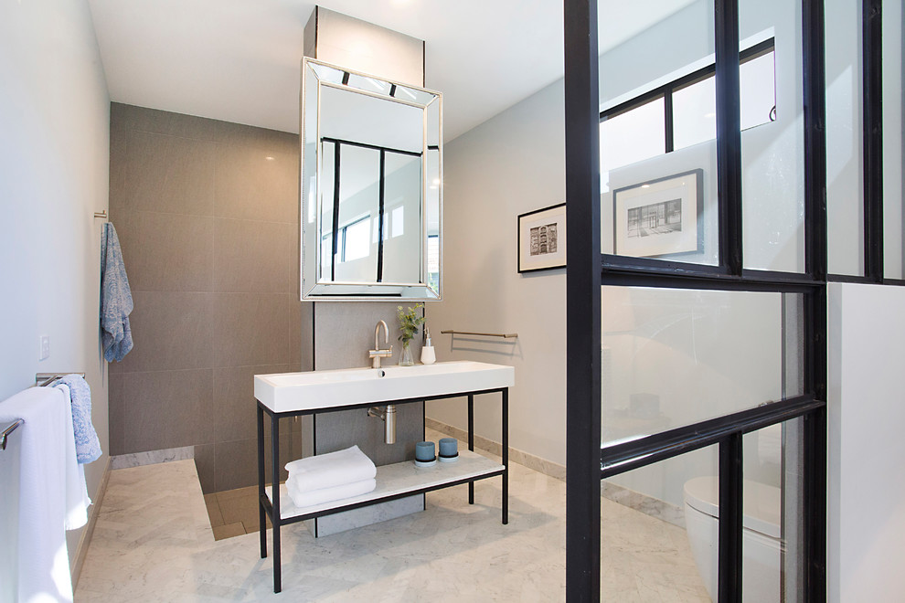 На фото: главная ванная комната в современном стиле с черными фасадами, японской ванной, открытым душем, инсталляцией, серой плиткой, керамогранитной плиткой, серыми стенами, мраморным полом, белым полом, открытым душем и консольной раковиной с