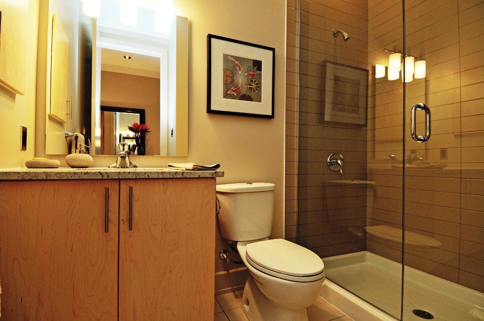 Foto på ett litet funkis badrum, med ett undermonterad handfat, släta luckor, skåp i ljust trä, granitbänkskiva, en dusch i en alkov, beige kakel, keramikplattor, beige väggar och klinkergolv i porslin