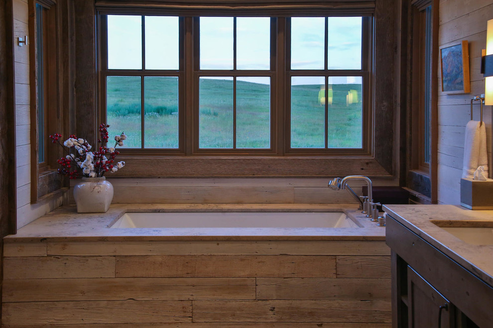 Exemple d'une grande salle de bain principale tendance en bois vieilli avec un placard à porte plane, une baignoire encastrée, un carrelage gris, un carrelage de pierre, un mur gris, un sol en carrelage de céramique, un lavabo encastré et un plan de toilette en stéatite.