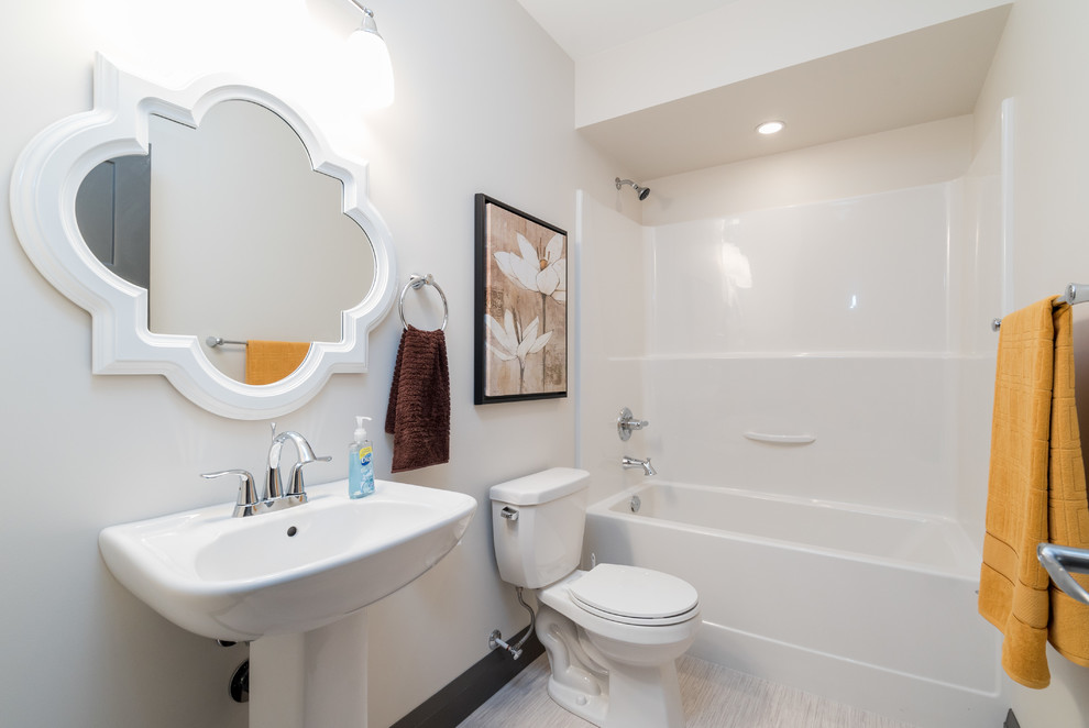 Diseño de cuarto de baño clásico renovado pequeño con lavabo con pedestal, bañera empotrada, combinación de ducha y bañera, sanitario de una pieza, paredes grises, suelo de linóleo y aseo y ducha