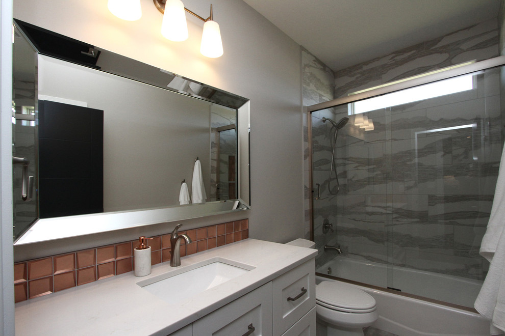 Modelo de cuarto de baño moderno con puertas de armario grises, ducha abierta, baldosas y/o azulejos grises, lavabo bajoencimera y suelo blanco