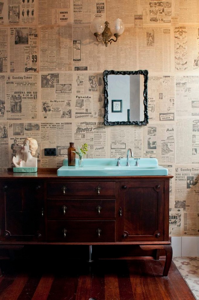 Modelo de cuarto de baño ecléctico con lavabo encastrado, puertas de armario de madera en tonos medios, suelo de madera oscura, paredes multicolor y armarios con paneles empotrados