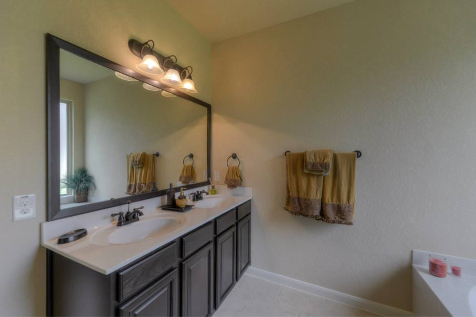 Mid-sized transitional master ceramic tile alcove bathtub photo in Austin with raised-panel cabinets, dark wood cabinets, beige walls, an integrated sink and solid surface countertops