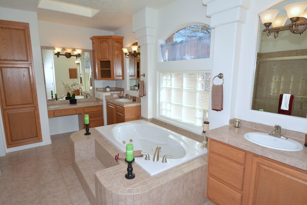 Klassisk inredning av ett stort en-suite badrum, med ett nedsänkt handfat, skåp i shakerstil, skåp i mellenmörkt trä, kaklad bänkskiva, ett platsbyggt badkar, en dubbeldusch, en toalettstol med separat cisternkåpa, beige kakel, keramikplattor, vita väggar och klinkergolv i keramik