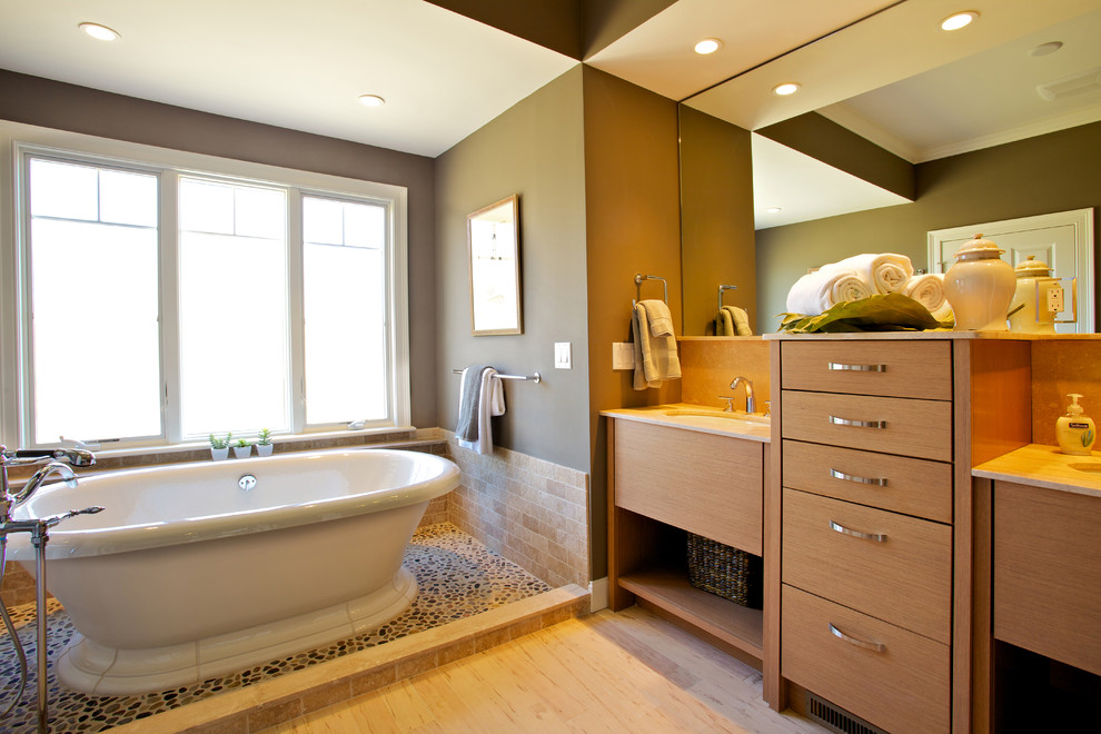 Ejemplo de cuarto de baño tradicional renovado con lavabo bajoencimera, armarios con paneles lisos, puertas de armario de madera clara, bañera exenta, baldosas y/o azulejos beige y ventanas
