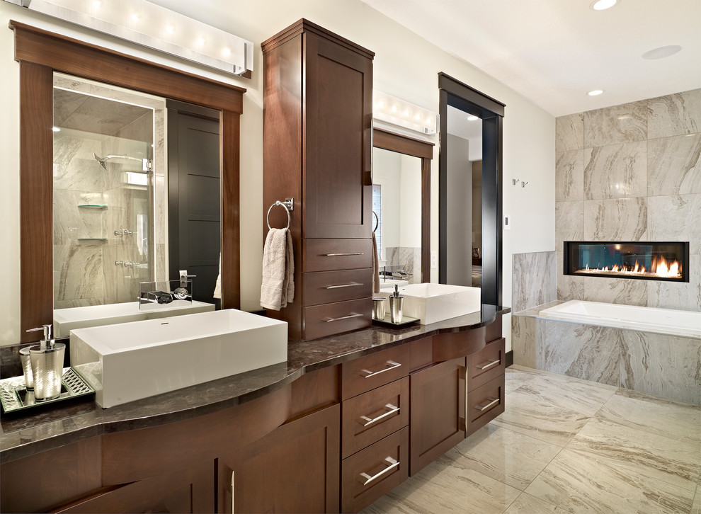Idée de décoration pour une salle de bain design en bois foncé avec une vasque, un placard à porte shaker, une baignoire posée, un carrelage gris et un mur blanc.