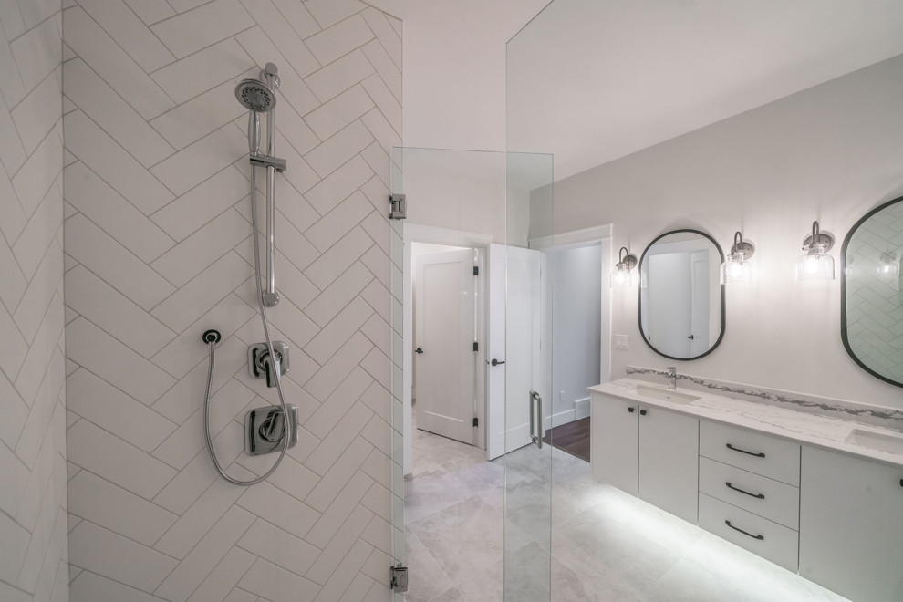 Inredning av ett modernt mellanstort vit vitt en-suite badrum, med skåp i shakerstil, vita skåp, ett fristående badkar, en dusch i en alkov, en toalettstol med hel cisternkåpa, vit kakel, vita väggar, ett undermonterad handfat, grått golv och dusch med gångjärnsdörr