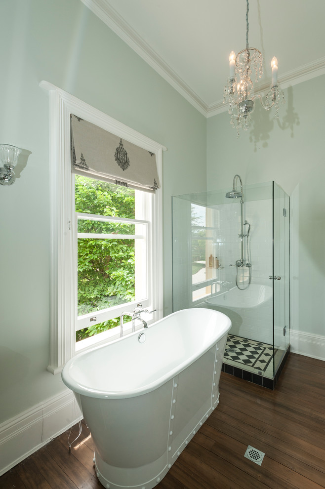 Immagine di una stanza da bagno con doccia tradizionale di medie dimensioni con vasca con piedi a zampa di leone, doccia ad angolo, piastrelle bianche, piastrelle in ceramica, pareti verdi e parquet scuro