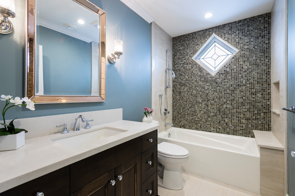 Bild på ett mellanstort vintage badrum, med luckor med infälld panel, skåp i mörkt trä, ett badkar i en alkov, en dusch i en alkov, flerfärgad kakel, glaskakel, blå väggar, klinkergolv i porslin, ett undermonterad handfat, bänkskiva i kvartsit och beiget golv