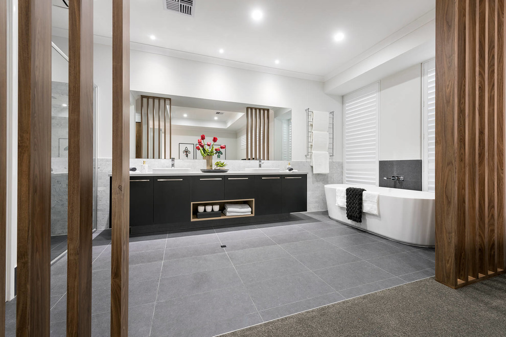 This is an example of a large contemporary ensuite bathroom in Perth with flat-panel cabinets, black cabinets, a freestanding bath, a corner shower, a one-piece toilet, white tiles, porcelain tiles, white walls, porcelain flooring, a built-in sink, engineered stone worktops, grey floors and a hinged door.