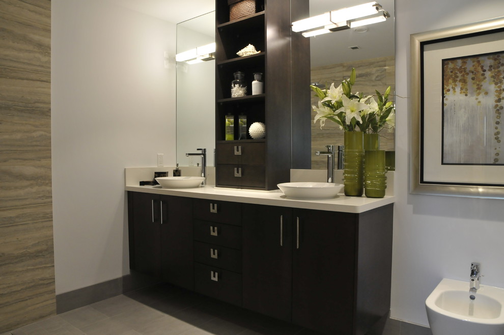 Photo of a medium sized contemporary ensuite bathroom in Vancouver with white walls, flat-panel cabinets, dark wood cabinets, a wall mounted toilet, mirror tiles, ceramic flooring, a vessel sink, laminate worktops and grey floors.