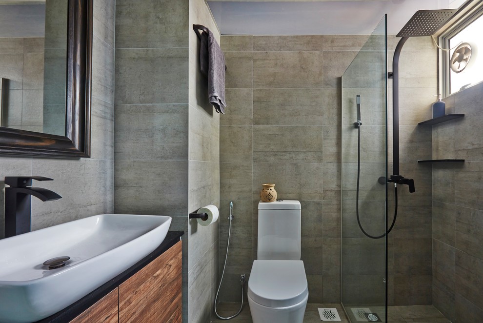 На фото: ванная комната в стиле модернизм с плоскими фасадами, фасадами цвета дерева среднего тона, душевой комнатой, унитазом-моноблоком, серой плиткой, серыми стенами, душевой кабиной, настольной раковиной, серым полом и открытым душем с