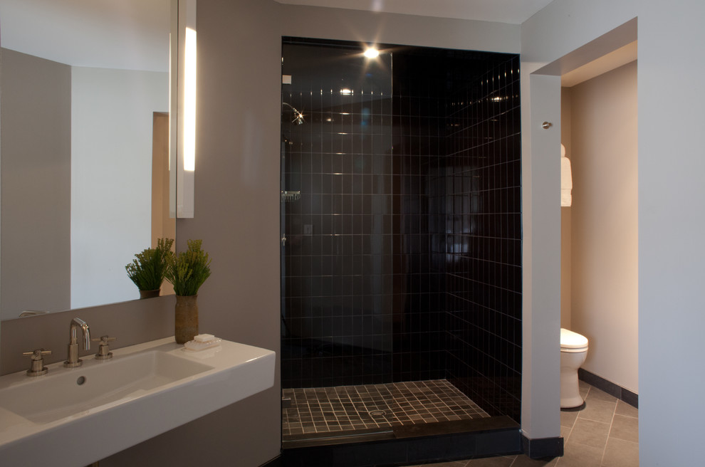 Inspiration for a medium sized contemporary shower room bathroom in New York with a corner shower, a one-piece toilet, black tiles, metro tiles, grey walls, slate flooring, a wall-mounted sink, engineered stone worktops, grey floors, an open shower, white worktops and a single sink.