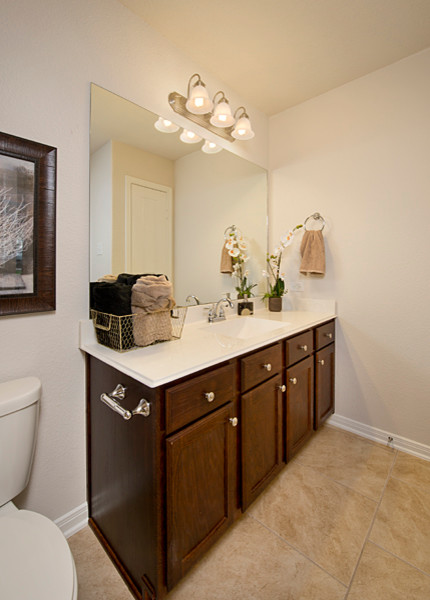 Cette image montre une salle d'eau traditionnelle en bois foncé de taille moyenne avec un placard avec porte à panneau surélevé, WC séparés, un mur beige, un sol en carrelage de porcelaine, un lavabo encastré, un plan de toilette en quartz modifié, un sol beige et un plan de toilette blanc.