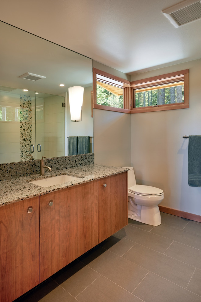 This is an example of a medium sized contemporary shower room bathroom in Seattle with flat-panel cabinets, medium wood cabinets, an alcove shower, a one-piece toilet, white tiles, porcelain tiles, beige walls, porcelain flooring, a submerged sink and solid surface worktops.