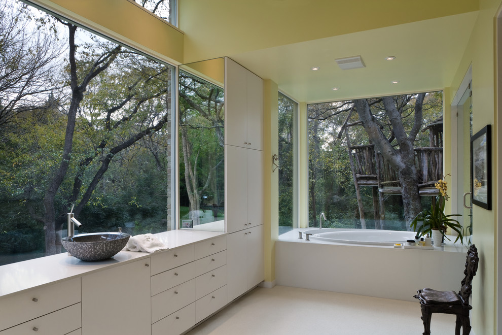 Diseño de cuarto de baño principal actual de tamaño medio con lavabo sobreencimera, armarios con paneles lisos, puertas de armario blancas, bañera encastrada y paredes amarillas