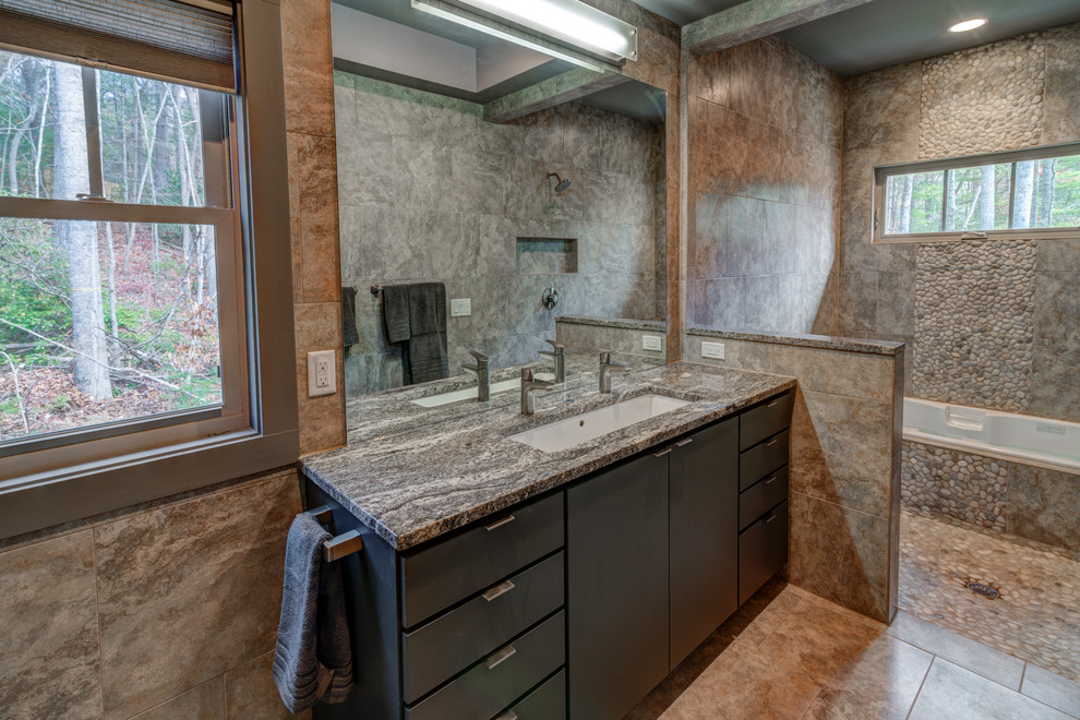 На фото: главная ванная комната в современном стиле с раковиной с несколькими смесителями, плоскими фасадами, темными деревянными фасадами, столешницей из гранита, накладной ванной, душем над ванной, галечной плиткой и полом из керамогранита с