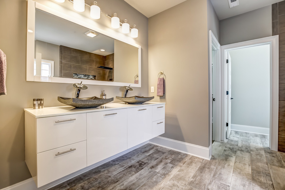 Bathroom - large transitional master brown tile and porcelain tile vinyl floor and brown floor bathroom idea in Other with flat-panel cabinets, white cabinets, gray walls, a vessel sink and solid surface countertops