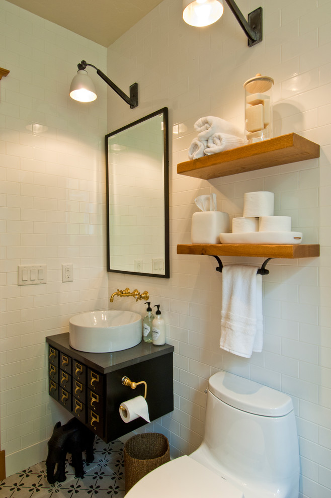 Foto på ett mellanstort eklektiskt badrum, med svarta skåp, ett fristående badkar, en toalettstol med hel cisternkåpa, vit kakel, tunnelbanekakel, vita väggar, ett fristående handfat och bänkskiva i kvarts