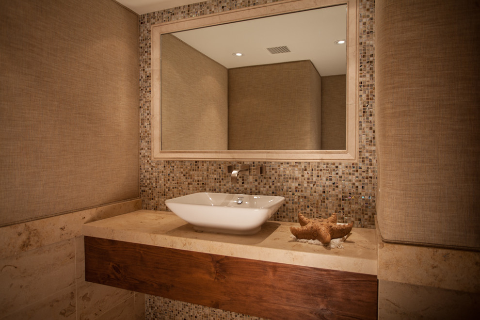 Cette image montre une grande douche en alcôve principale design en bois brun avec un plan de toilette en marbre, un carrelage beige, un placard avec porte à panneau encastré, un carrelage de pierre, un mur beige, un sol en calcaire et un lavabo encastré.